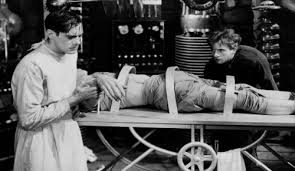 Image of Frankenstein's monster on the operating table, with Dr. Frankenstein and Igor attending, from the 1931 Frankenstein movie